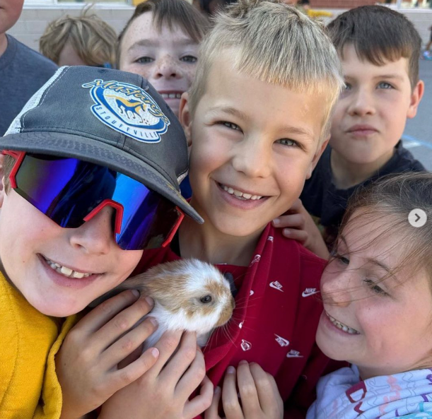 Excited children gather around a lop eared bunny as an example of best classroom pets