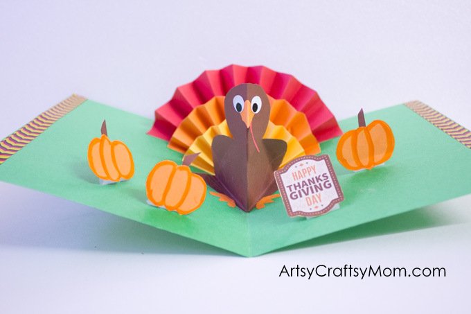 A pop up turkey sits in the fold of a card made from green construction paper