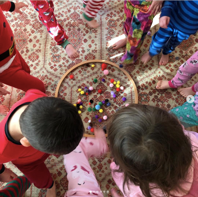 Children play a game trying to pick up pom poms with their toes as an example of Pajama Day ideas and activities