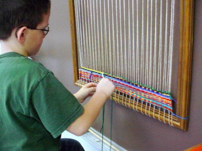 A boy sits weaving.