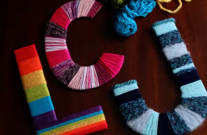 Cardboard alphabet letters wrapped in stripes of colorful yarn