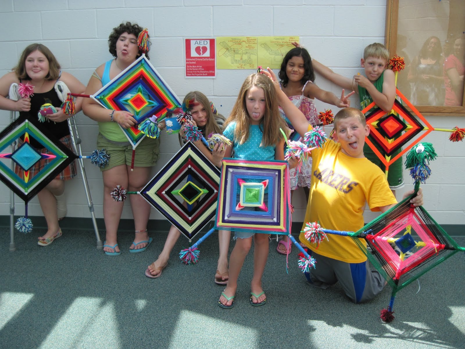 Third graders holding giant gods-eye weavings