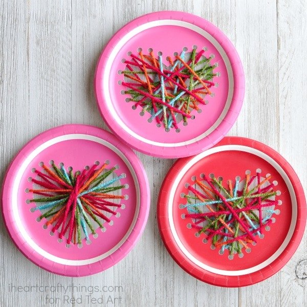 Red and pink paper plates with yarn hearts woven from holes punched into them