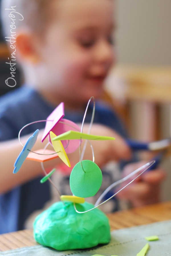 A child using wire, clay, and foam shapes to create a sculpture
