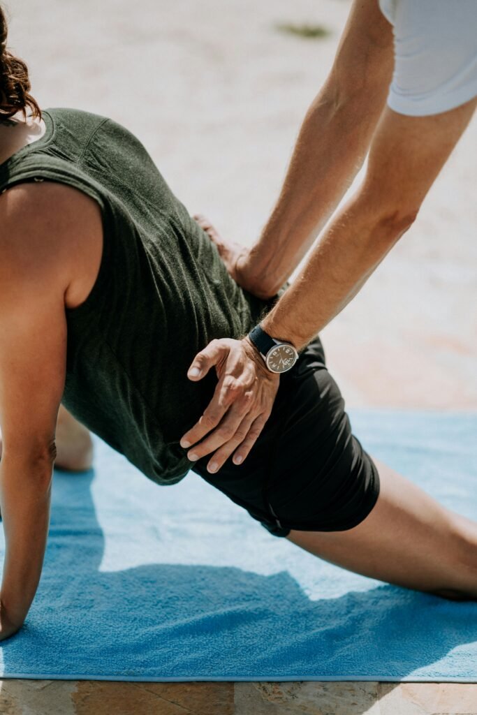 A physical therapist presses on a man's back as he stretches on a mat