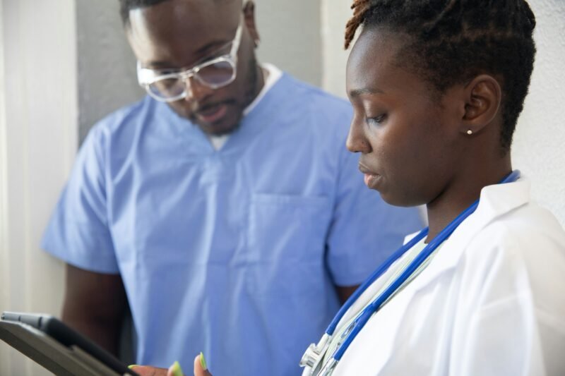 A nurse practitioner speaks with a colleague as they look at some notes