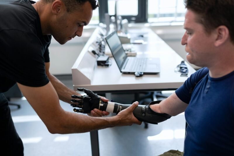 A man helps to fit a prosthetic arm onto another man