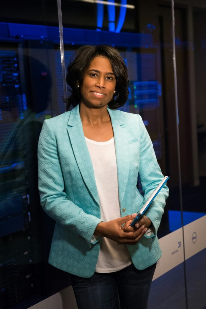A chief technology officer holds a laptop and stands in front of a server room