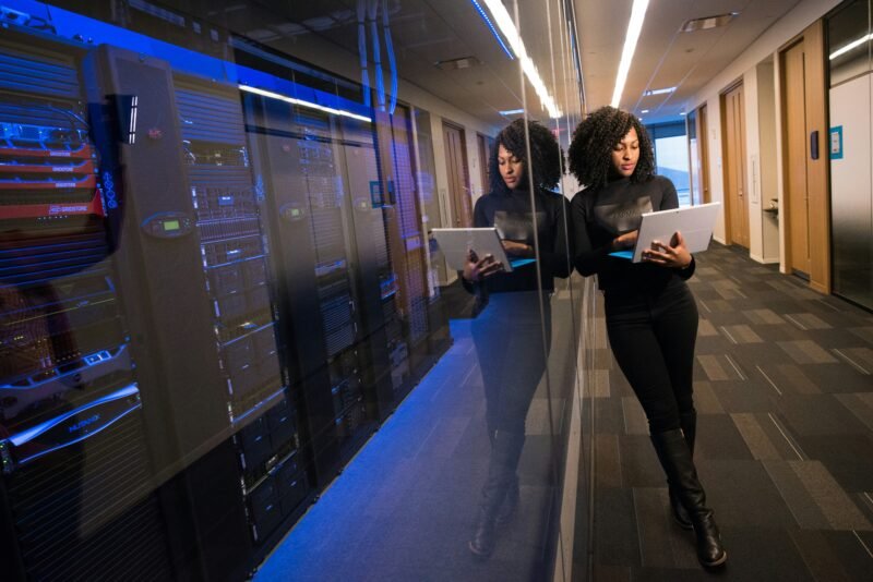 A cloud engineer looks at a laptop while standing by a bank of servers