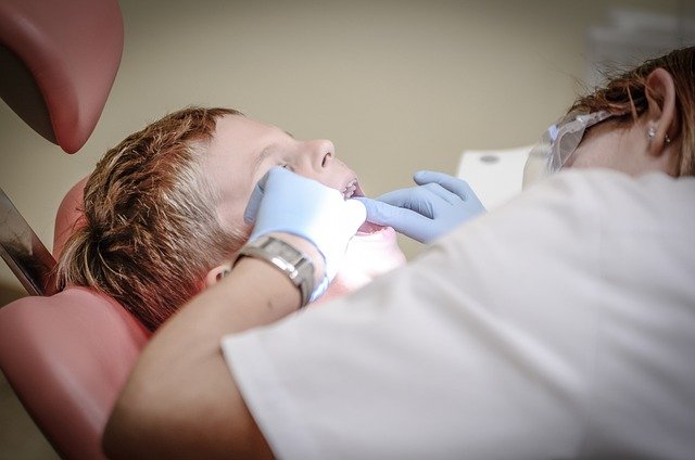 A dental hygienist works on a child's teeth