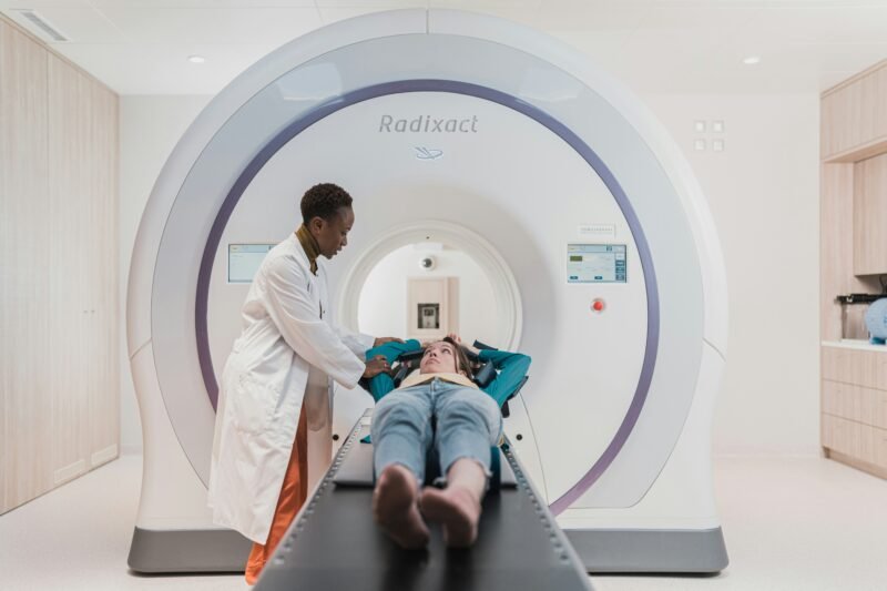 A radiology technician stands by a patient about to have an MRI