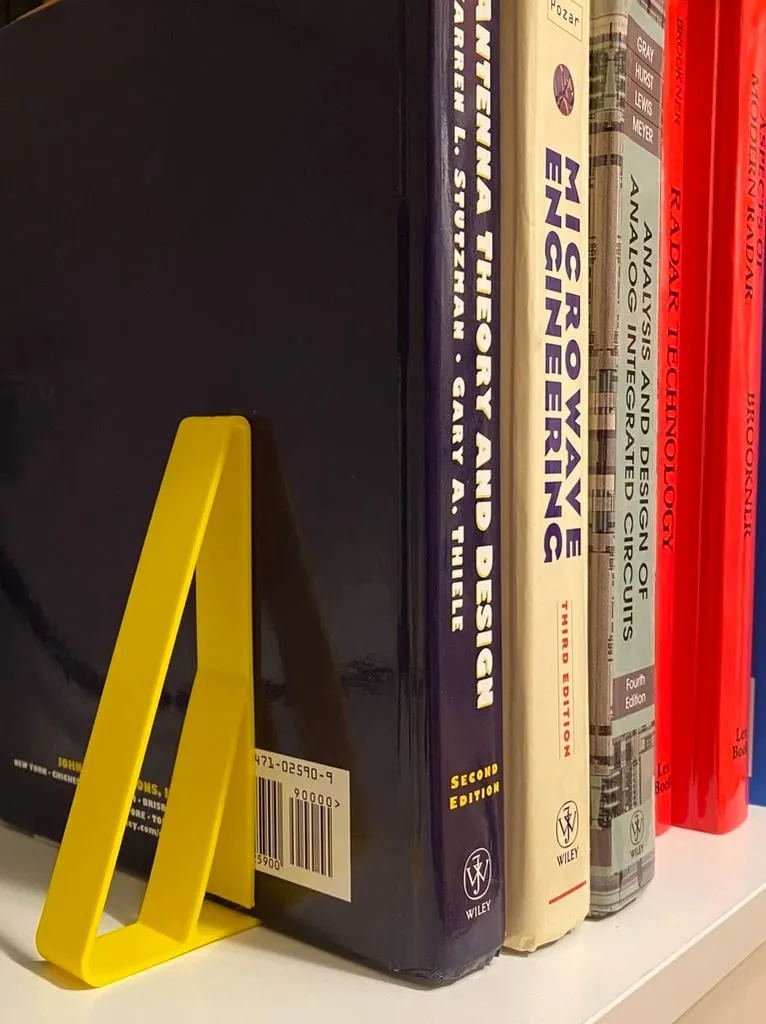 A yellow bookend holds up several books.