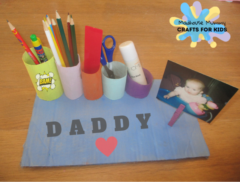 A desk organizer is made of different sized paper tubes with different colored construction paper on them as an example of father's day gifts for kids