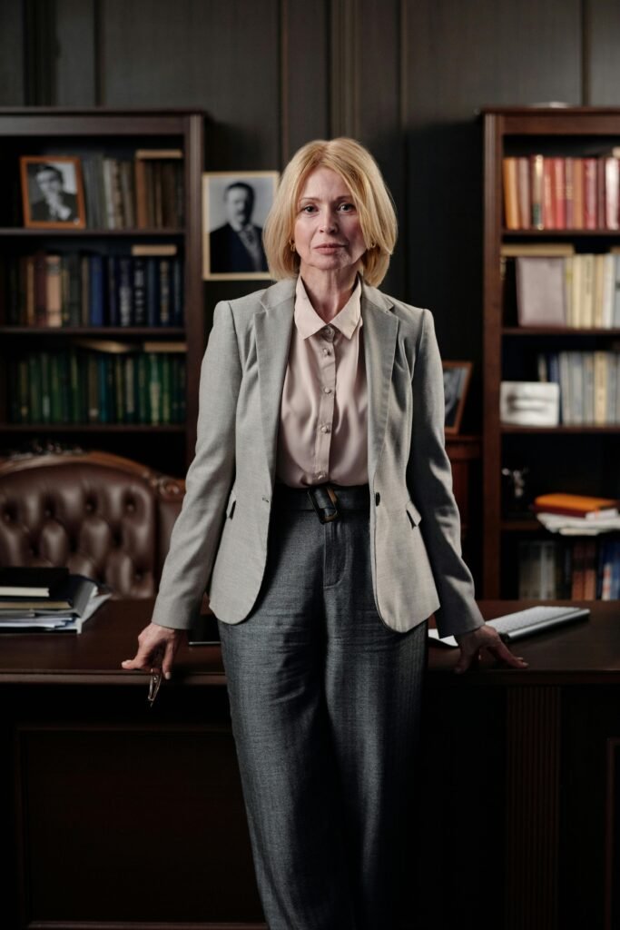 A woman is standing in front of a fancy desk in a fancy office.