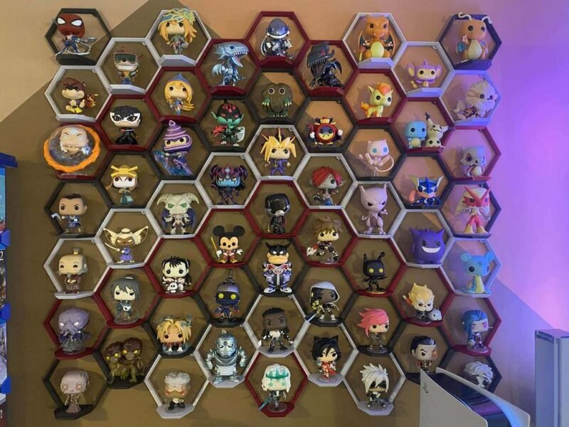 A large display is made up of smaller hexagonal containers that are holding Funko Pop figures. It is attached to a wall.