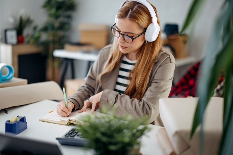 Woman writes down orders while working in her home office