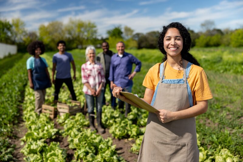 Happy female worker leading a group of farmers working at a plantation - agricultural activity concepts