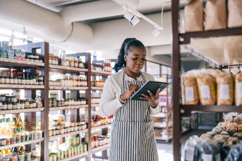 African employee seamlessly integrates technology into inventory management, using a digital tablet to track and organize items