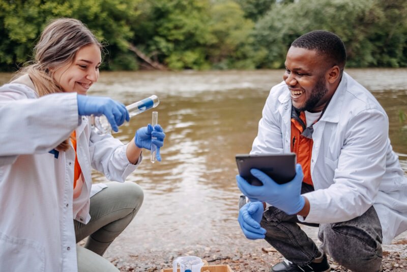 Two colleagues working together outdoor in nature analysing water quality in river