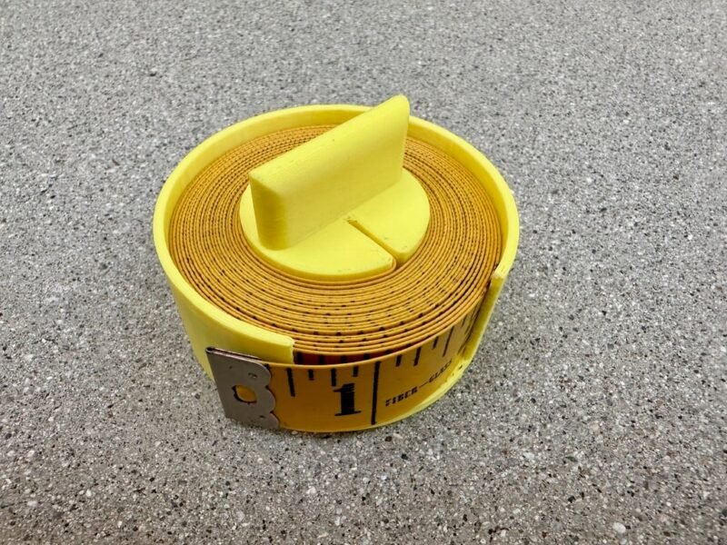 A yellow spool contains a fabric measuring tape within in in this example of 3D printing ideas.