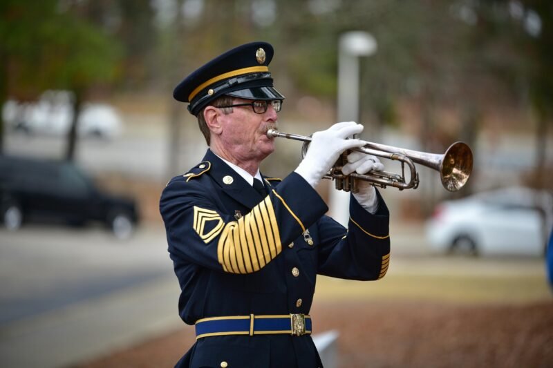 A man in a military uniform is playing a trumpet. 