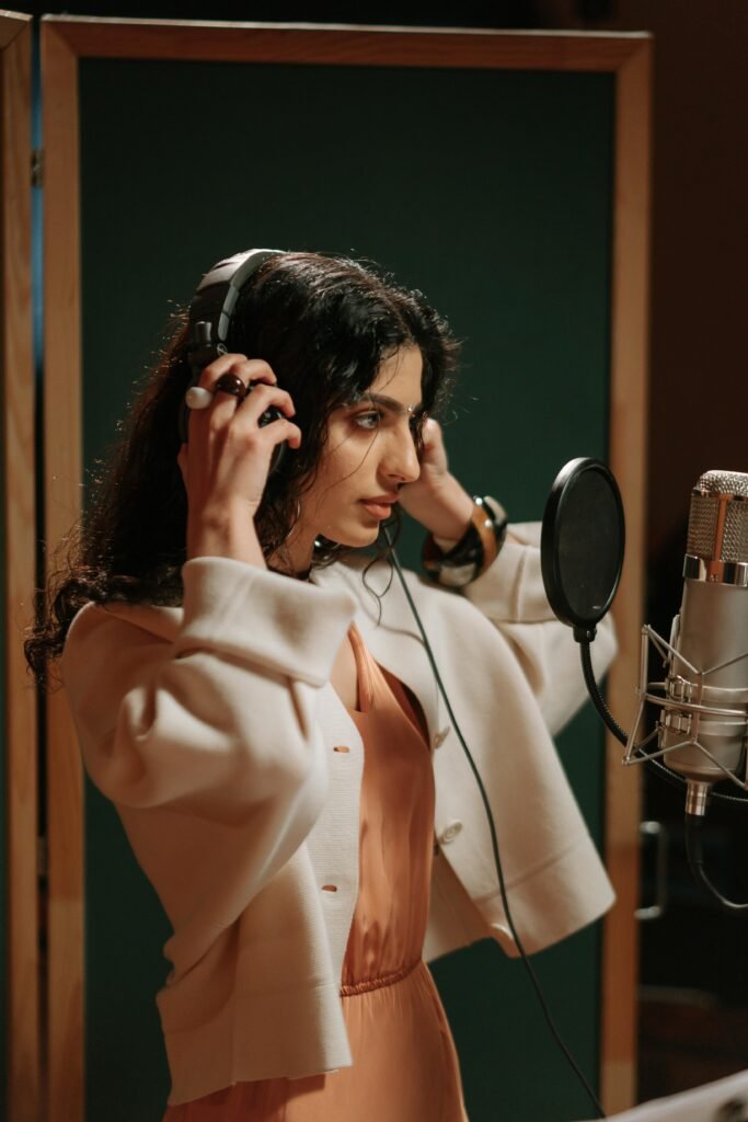 A woman is seen in a recording studio wearing headphones in front of a microphone in this example of music careers