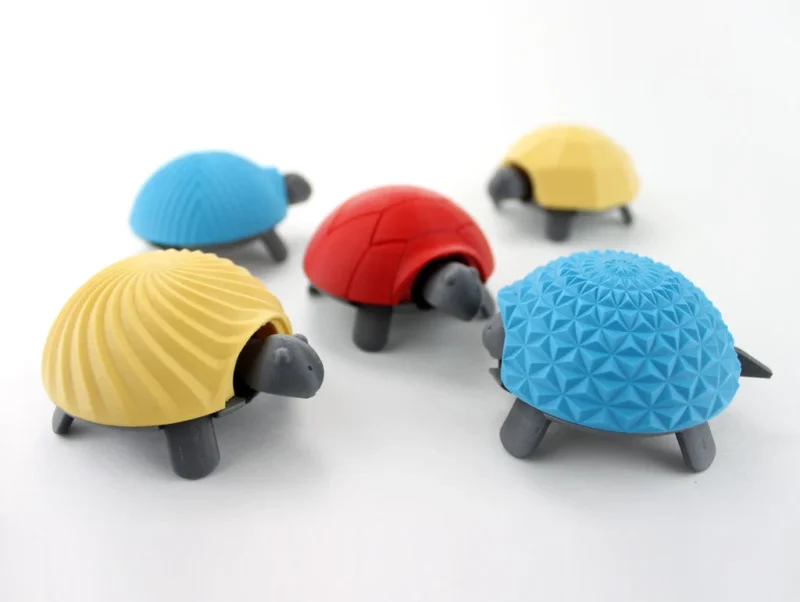 Five 3D printed turtles are shown with blue, yellow, and red shells.