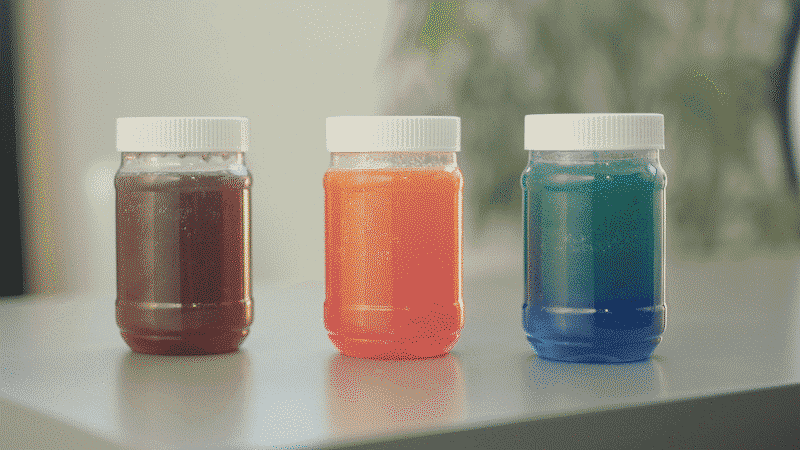 Small plastic jars with white lids with colored liquid inside