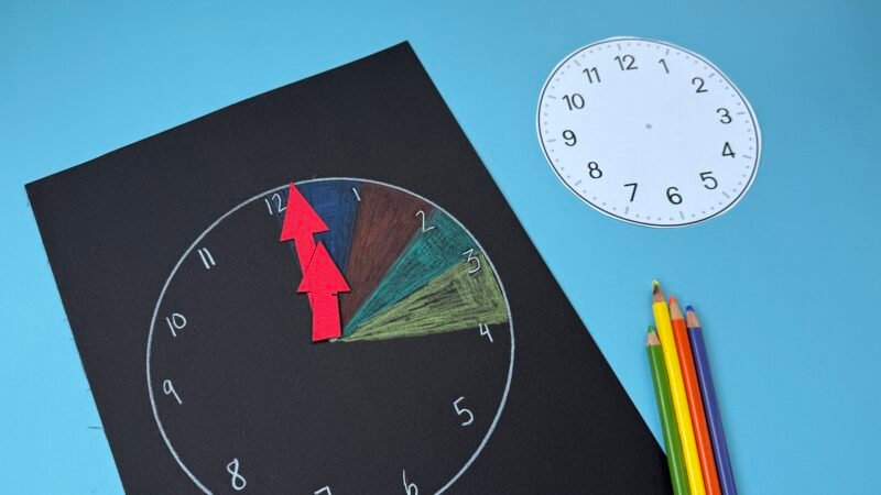 Black paper with multi-colored clock drawing on it