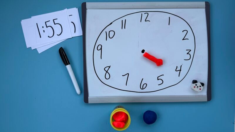 Piece of paper with clock drawn on it and piece of play doh acting as hands of clock