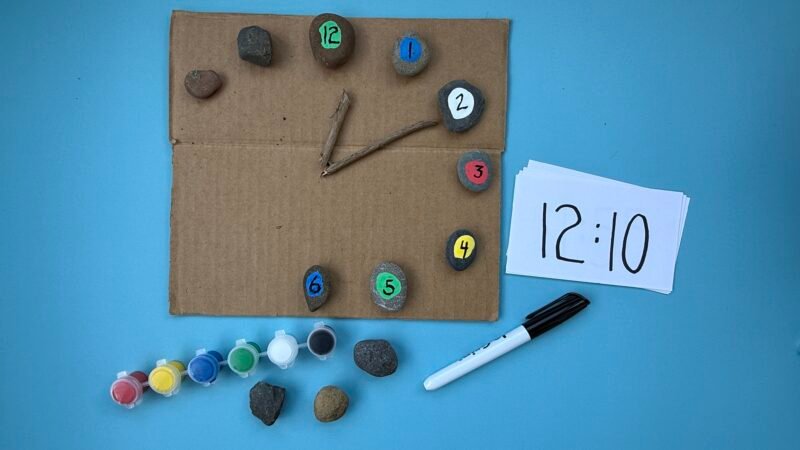 piece of cardboard with rocks and clock hands telling time