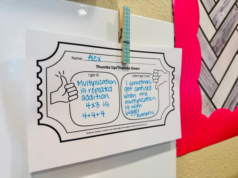 a thumbs up and thumbs down exit ticket hung up on a classroom whiteboard