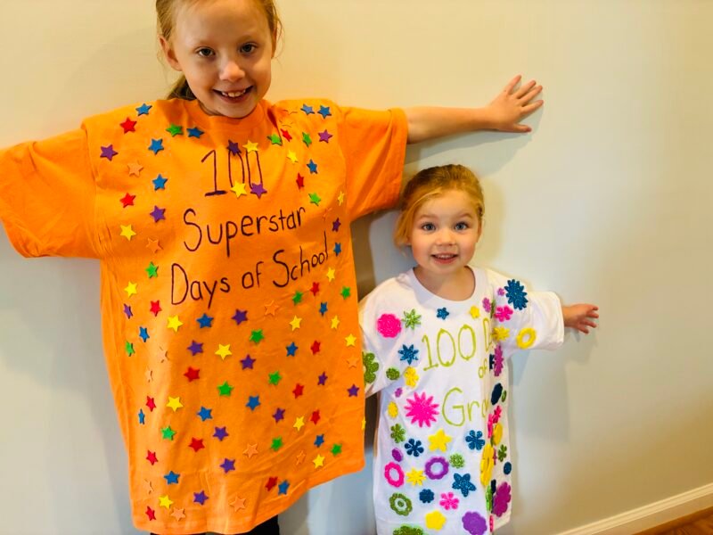 two students showing off shirts they decorated to celebrate the 100 days of school