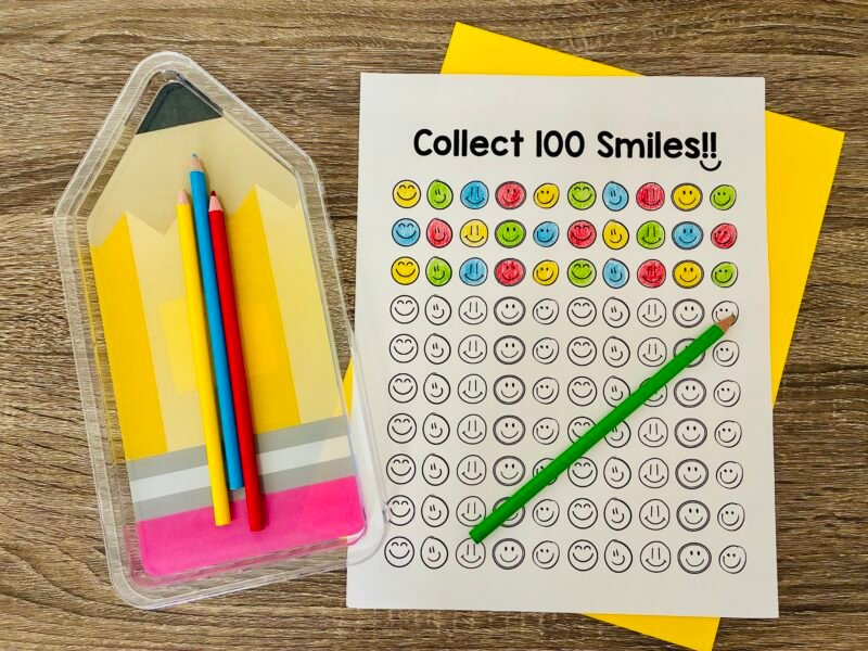 an image of 100 smiley faces on a printable with a few colored in to celebrate the 100th day of school