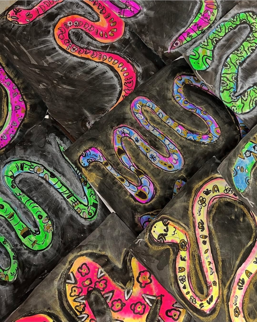 Neon snake drawings on black construction paper