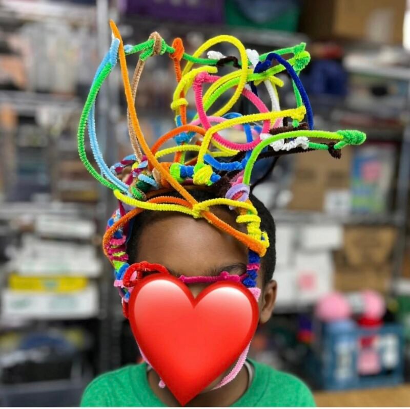 2nd grade art student wearing a hat made of pipe cleaners