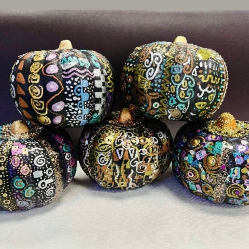 Pumpkins painted black and covered in designs using metallic markers