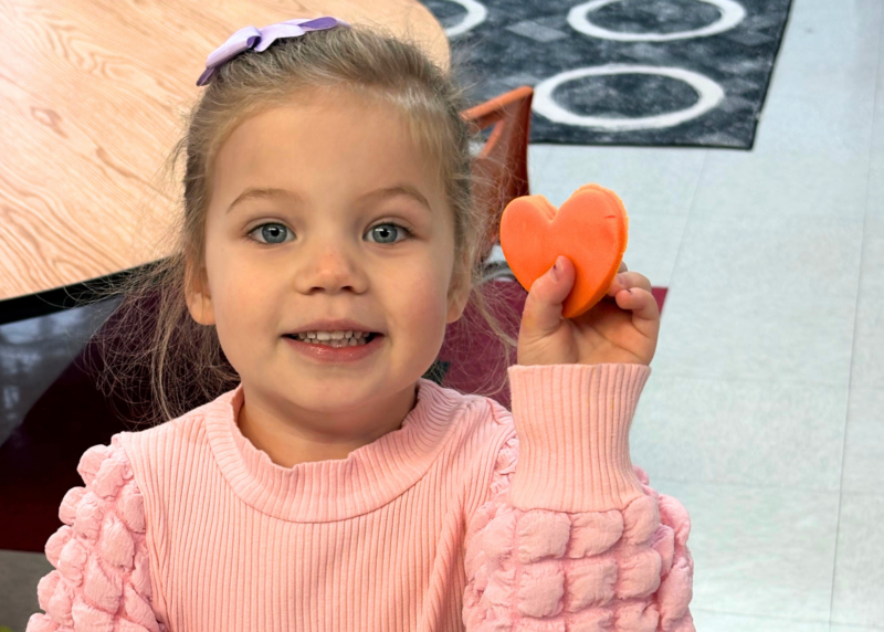 a student holding up clay in the shape of a heart as a form of art therapy