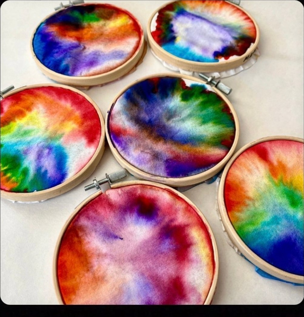 Colorful diffusing paper art designs mounted in embroidery hoops