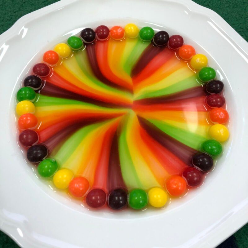 Science Projects for 2nd Graders an image of skittles in a shallow dish with water and their colors are combining to make a rainbow
